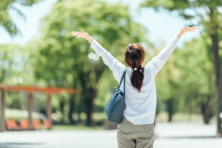 緑の中で両手を広げる女性。自分の感覚を信じて歩き出す、前向きな一歩を表している。